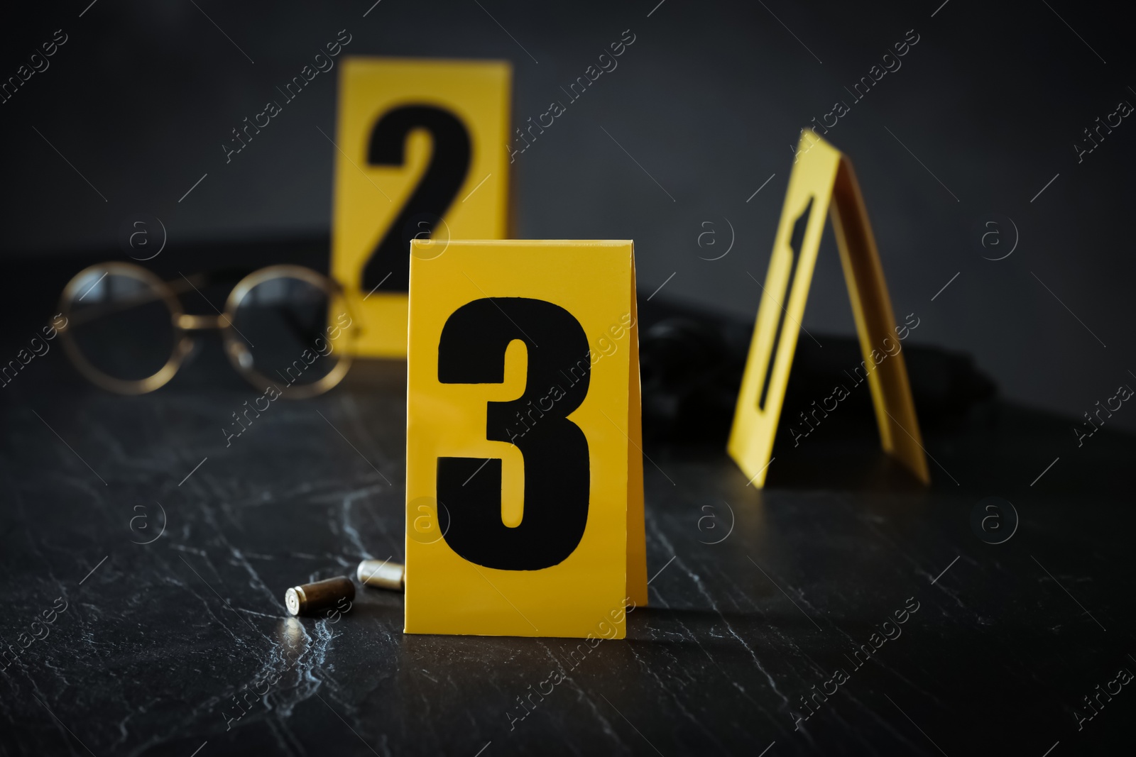 Photo of Shell casings and evidence marker on black slate table, closeup. Crime scene