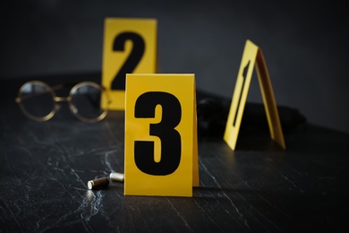 Photo of Shell casings and evidence marker on black slate table, closeup. Crime scene