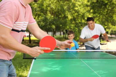 Family with child playing ping pong in park, closeup Photo of Family with child playing ping pong in park, closeup