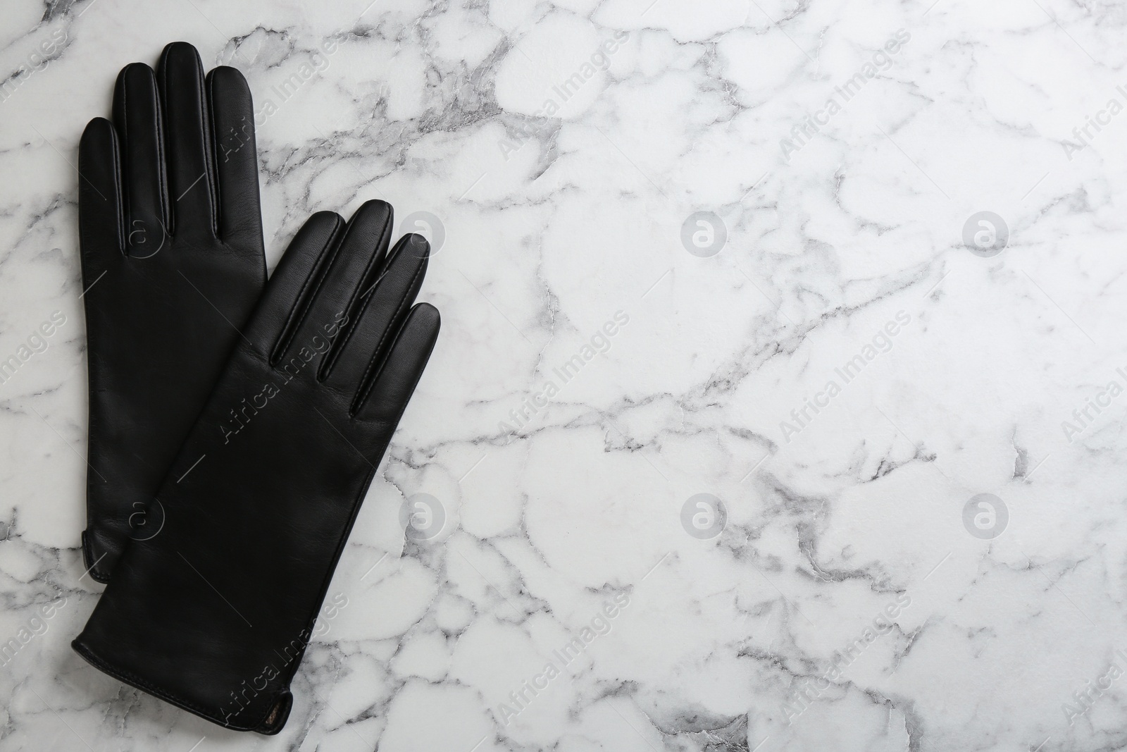 Stylish black leather gloves on white marble table, flat lay. Space for text Photo of Stylish black leather gloves on white marble table, flat lay. Space for text
