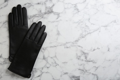 Stylish black leather gloves on white marble table, flat lay. Space for text Photo of Stylish black leather gloves on white marble table, flat lay. Space for text