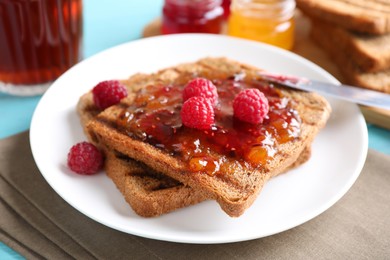 Tasty toast with raspberry jam and fresh berries for breakfast on table, closeup Image of Tasty toast with raspberry jam and fresh berries for breakfast on table, closeup