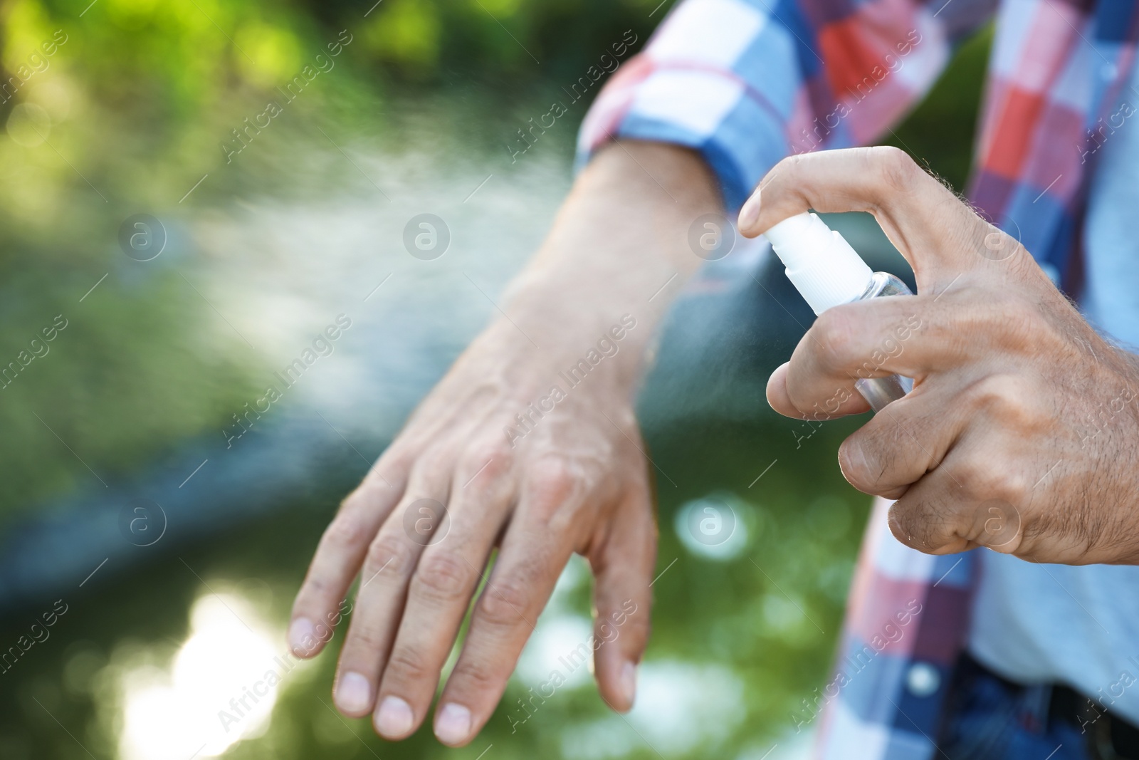 Man applying insect repellent onto hand outdoors, closeup Photo of Man applying insect repellent onto hand outdoors, closeup