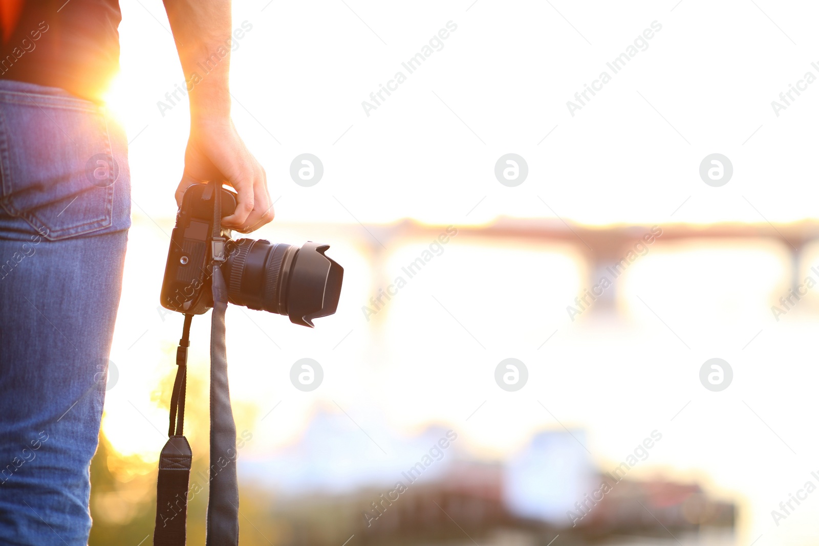 Photographer with professional camera outdoors on sunny day, closeup Photo of Photographer with professional camera outdoors on sunny day, closeup
