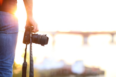 Photographer with professional camera outdoors on sunny day, closeup Photo of Photographer with professional camera outdoors on sunny day, closeup