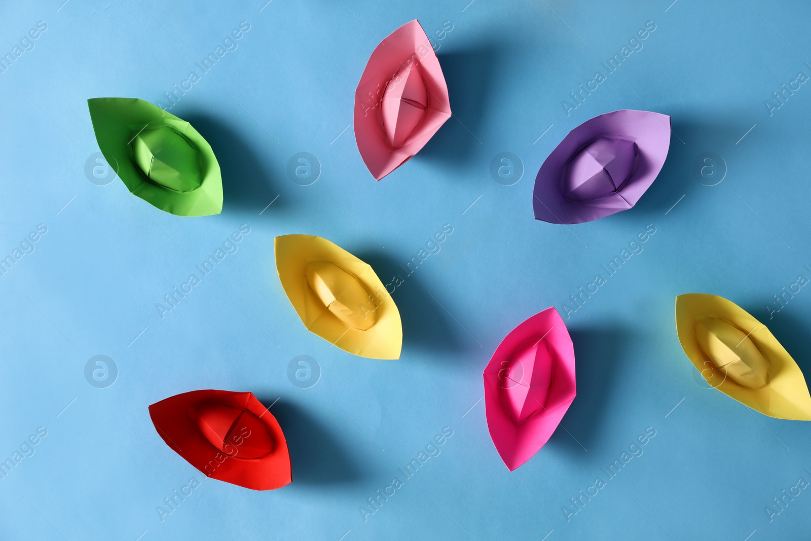 Colorful paper boats on light blue background, flat lay. Diversity concept Photo of Colorful paper boats on light blue background, flat lay. Diversity concept