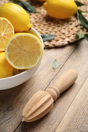 Squeezer with lemons on wooden table, closeup Photo of Squeezer with lemons on wooden table, closeup