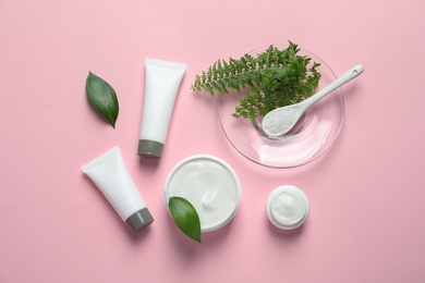 Different skin care cosmetic products with green leaves on color background, top view Photo of Different skin care cosmetic products with green leaves on color background, top view