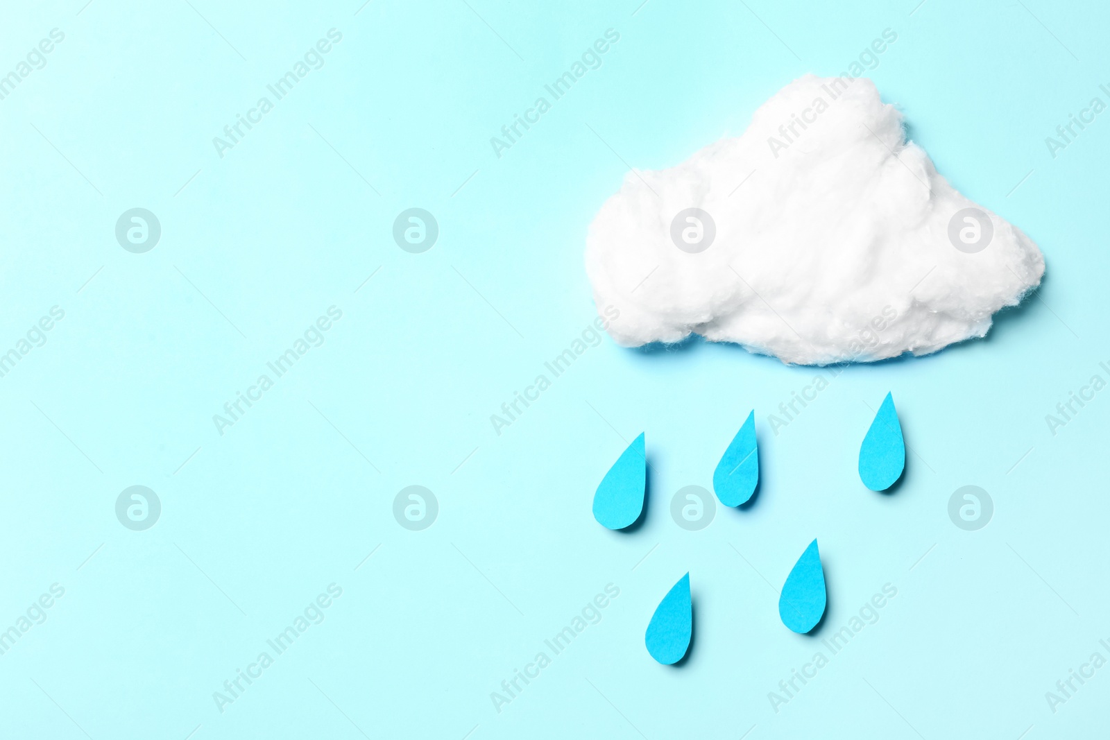 White cotton cloud and paper drops imitating rain on cyan background, flat lay. Space for text Photo of White cotton cloud and paper drops imitating rain on cyan background, flat lay. Space for text