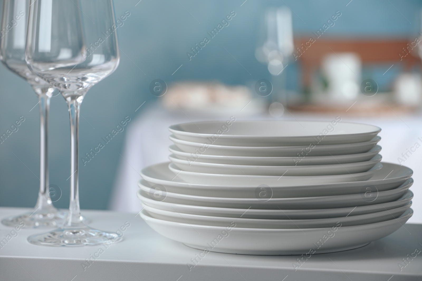 Stacked clean dishes and glasses on white shelf indoors Photo of Stacked clean dishes and glasses on white shelf indoors