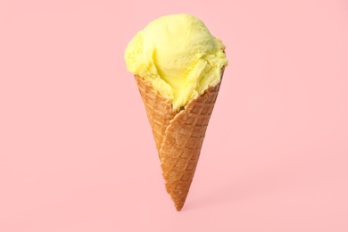Delicious yellow ice cream in waffle cone on pink background Photo of Delicious yellow ice cream in waffle cone on pink background