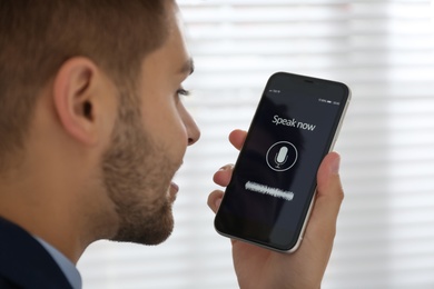 Young man using voice search on smartphone indoors, closeup Photo of Young man using voice search on smartphone indoors, closeup