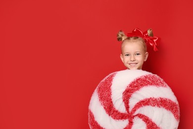 Cute little girl dressed as candy on red background, space for text. Christmas suit Image of Cute little girl dressed as candy on red background, space for text. Christmas suit