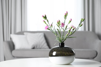 Vase with beautiful carnation flowers on table in living room, space for text. Stylish element of interior design Photo of Vase with beautiful carnation flowers on table in living room, space for text. Stylish element of interior design