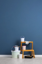 Set with decorator tools and paint on floor near color wall Photo of Set with decorator tools and paint on floor near color wall