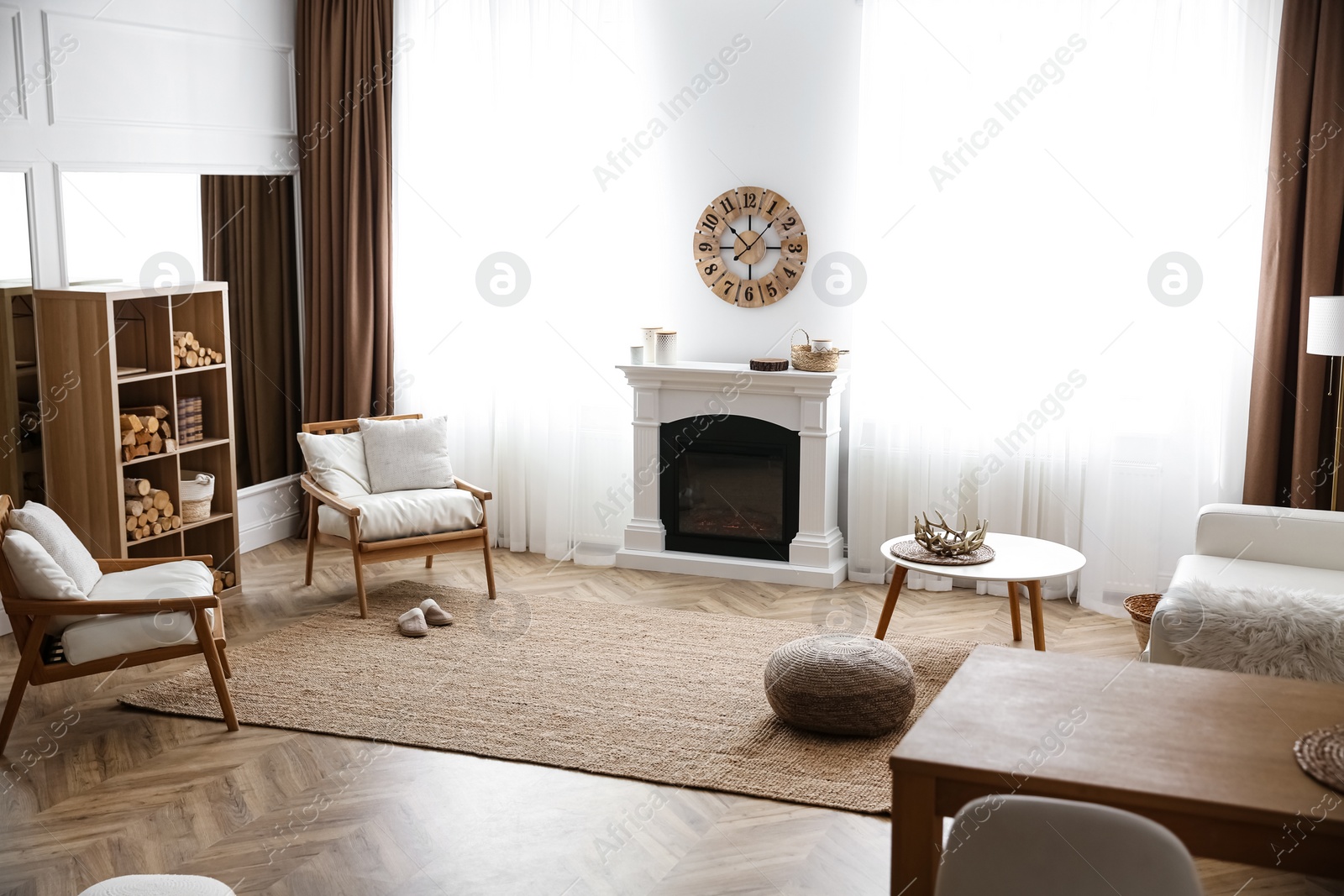 Elegant artificial fireplace and armchairs in room. Interior design Photo of Elegant artificial fireplace and armchairs in room. Interior design