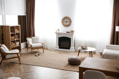 Elegant artificial fireplace and armchairs in room. Interior design Photo of Elegant artificial fireplace and armchairs in room. Interior design