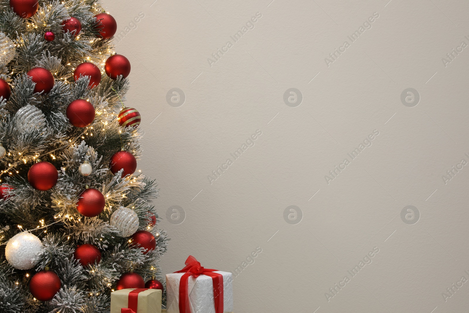 Beautiful decorated Christmas tree and presents on light background, space for text Photo of Beautiful decorated Christmas tree and presents on light background, space for text