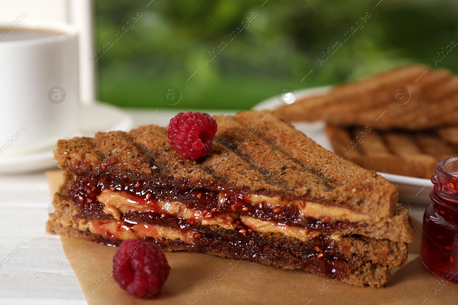 Tasty sandwich with raspberry jam and peanut butter for breakfast on table, closeup Image of Tasty sandwich with raspberry jam and peanut butter for breakfast on table, closeup