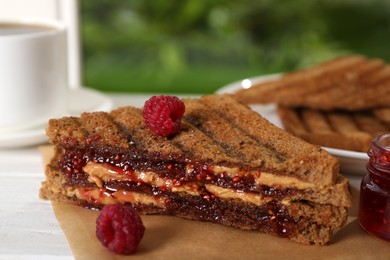 Tasty sandwich with raspberry jam and peanut butter for breakfast on table, closeup Image of Tasty sandwich with raspberry jam and peanut butter for breakfast on table, closeup