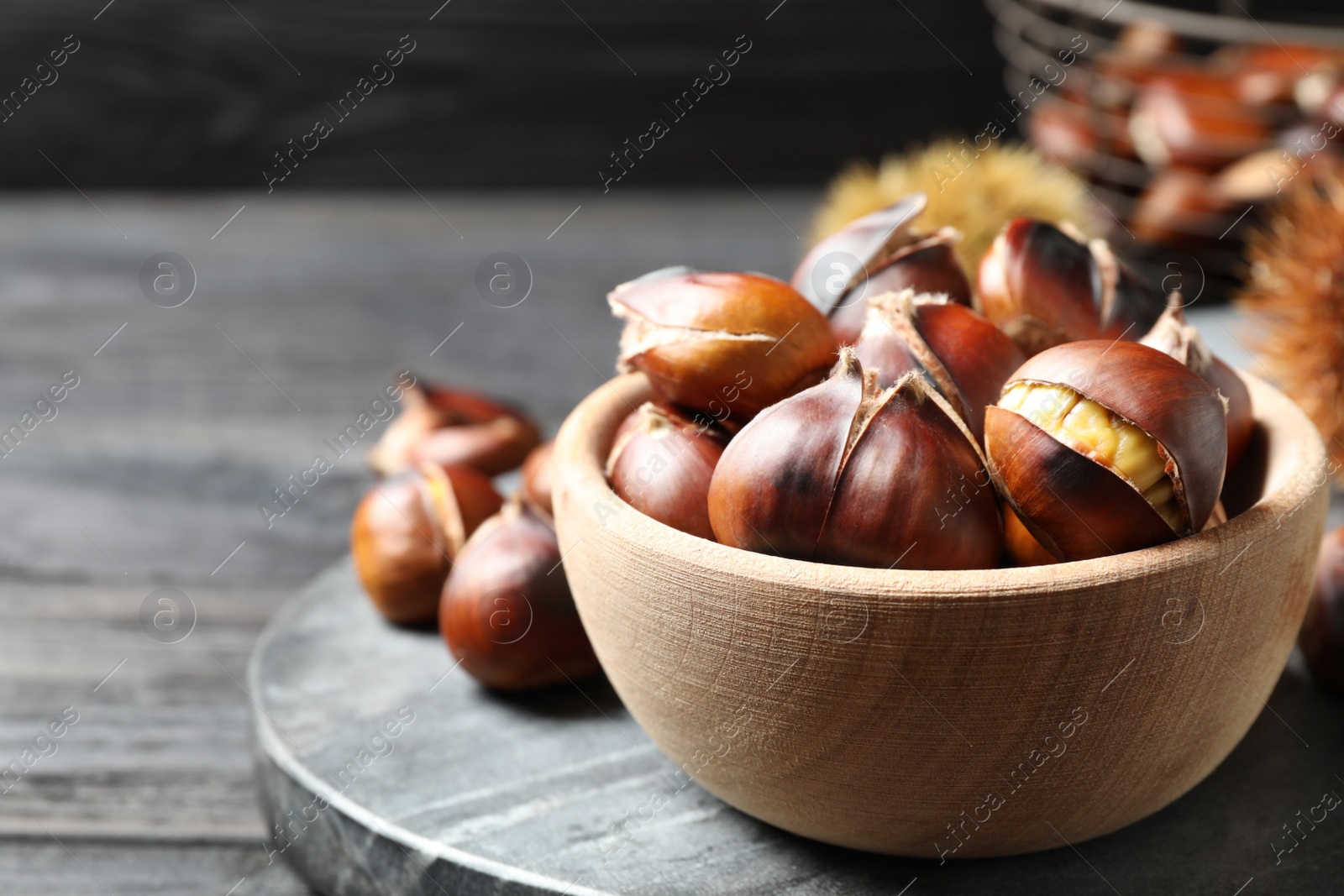 Delicious roasted edible chestnuts in wooden bowl on table, closeup Photo of Delicious roasted edible chestnuts in wooden bowl on table, closeup
