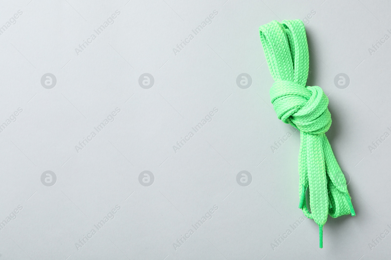 Green shoelaces on light background, top view. Space for text Photo of Green shoelaces on light background, top view. Space for text