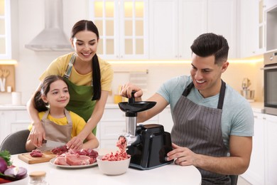 Happy family making dinner together in kitchen, father using modern meat grinder Photo of Happy family making dinner together in kitchen, father using modern meat grinder
