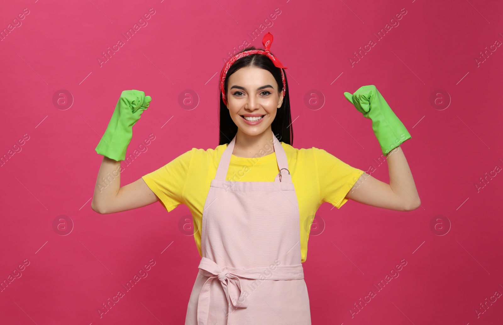 Young housewife wearing rubber gloves on pink background Photo of Young housewife wearing rubber gloves on pink background