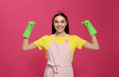 Young housewife wearing rubber gloves on pink background Photo of Young housewife wearing rubber gloves on pink background