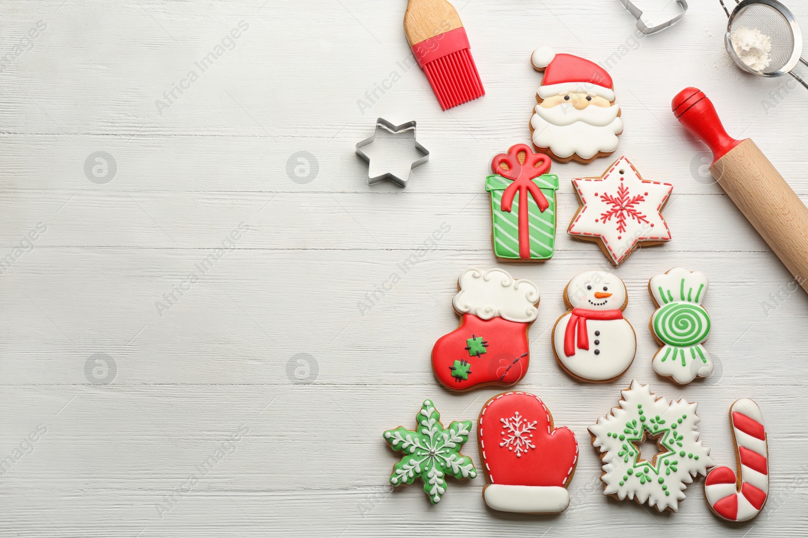 Kitchen utensils near Christmas tree shape made of delicious gingerbread cookies on white wooden table, flat lay. Space for text Photo of Kitchen utensils near Christmas tree shape made of delicious gingerbread cookies on white wooden table, flat lay. Space for text