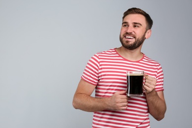 Handsome man with cold kvass on light grey background. Traditional Russian summer drink Photo of Handsome man with cold kvass on light grey background. Traditional Russian summer drink