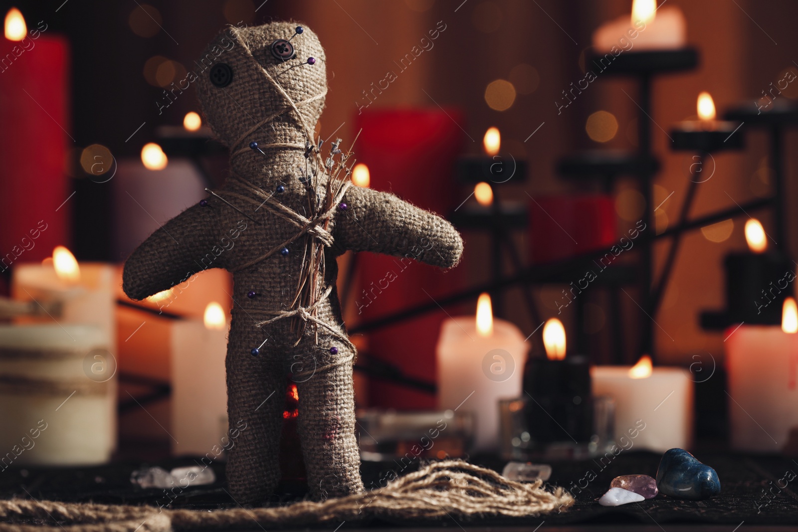 Voodoo doll with pins and dried flowers on table in room, space for text. Curse ceremony Photo of Voodoo doll with pins and dried flowers on table in room, space for text. Curse ceremony