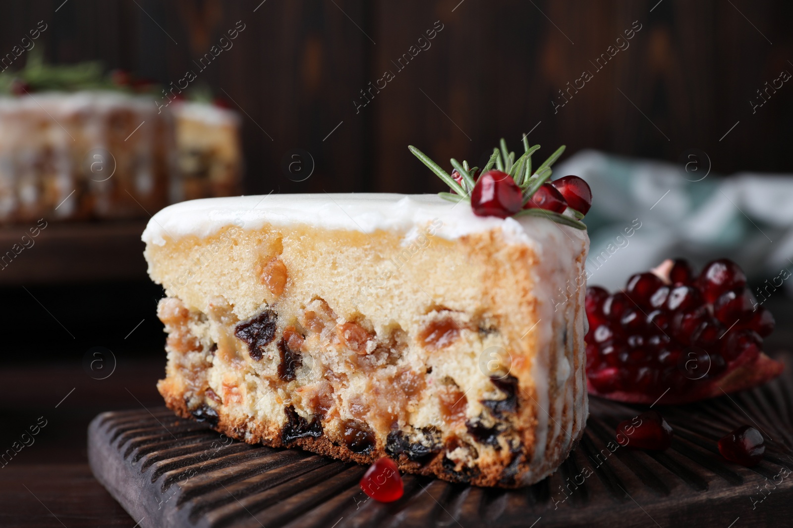 Piece of traditional homemade Christmas cake and fresh pomegranate on wooden board, closeup Photo of Piece of traditional homemade Christmas cake and fresh pomegranate on wooden board, closeup