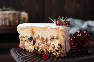 Piece of traditional homemade Christmas cake and fresh pomegranate on wooden board, closeup Photo of Piece of traditional homemade Christmas cake and fresh pomegranate on wooden board, closeup