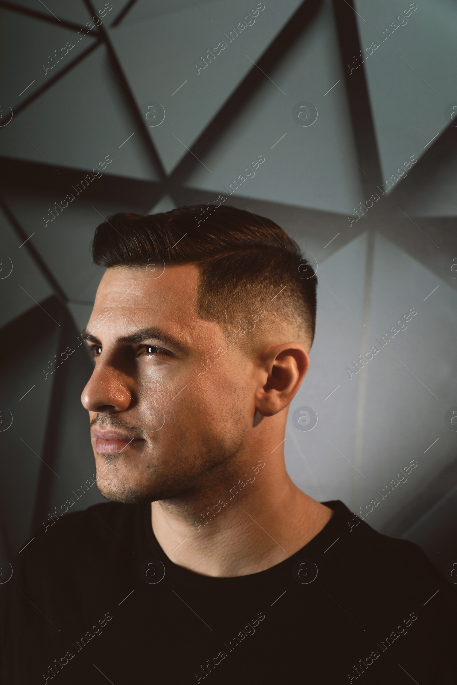 Handsome man with trendy hairstyle near dark wall Photo of Handsome man with trendy hairstyle near dark wall