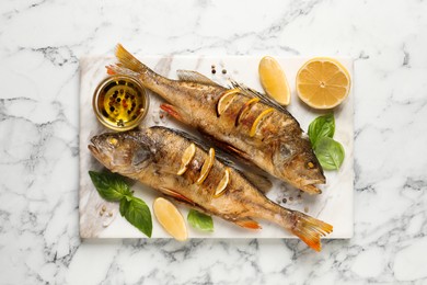 Tasty homemade roasted perches served on white marble table, top view. River fish Photo of Tasty homemade roasted perches served on white marble table, top view. River fish