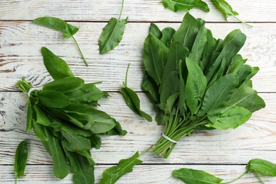 Fresh green sorrel leaves on white wooden table, flat lay Photo of Fresh green sorrel leaves on white wooden table, flat lay