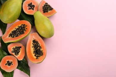 Fresh ripe papaya fruits with green leaves on pink background, flat lay. Space for text Photo of Fresh ripe papaya fruits with green leaves on pink background, flat lay. Space for text