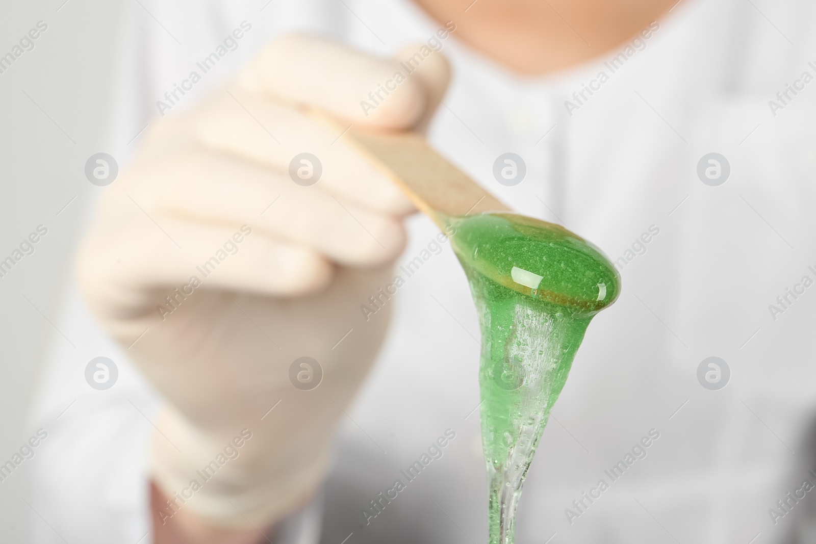 Woman holding spatula with hot depilatory wax, closeup Photo of Woman holding spatula with hot depilatory wax, closeup