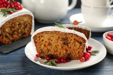 Photo of Traditional classic Christmas cake decorated with cranberries, pomegranate seeds and rosemary on wooden table