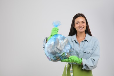 Woman holding full garbage bag on light background. Space for text Photo of Woman holding full garbage bag on light background. Space for text
