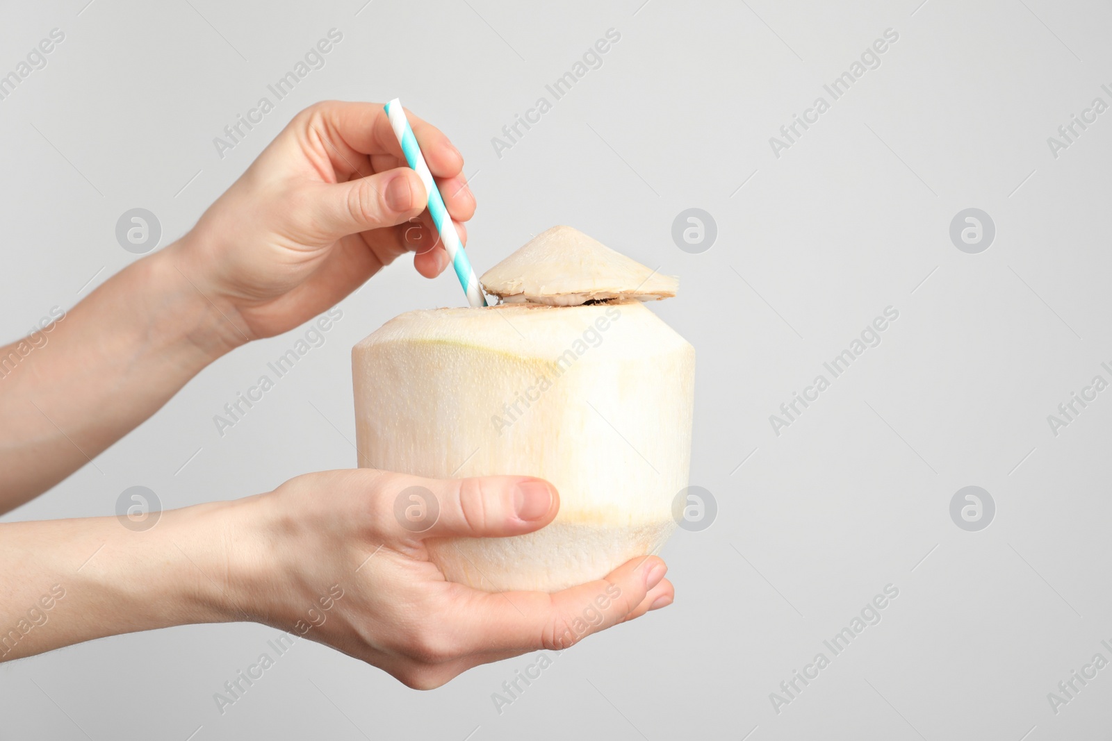 Woman with fresh coconut drink in nut on light background, closeup Photo of Woman with fresh coconut drink in nut on light background, closeup