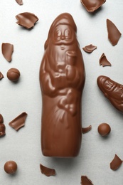 Flat lay composition with whole and broken chocolate Santa Claus candies on light grey table Photo of Flat lay composition with whole and broken chocolate Santa Claus candies on light grey table