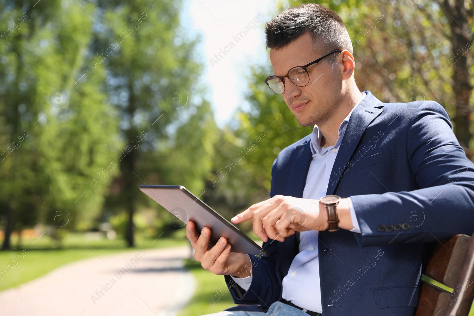 Man working with tablet on bench in park Photo of Man working with tablet on bench in park