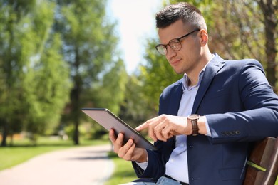 Man working with tablet on bench in park Photo of Man working with tablet on bench in park