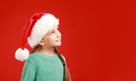 Happy little child in Santa hat on red background, space for text. Christmas celebration Image of Happy little child in Santa hat on red background, space for text. Christmas celebration