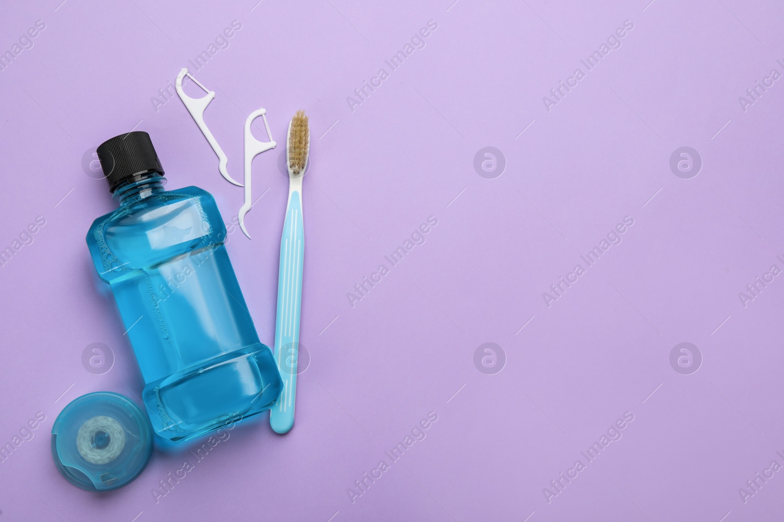 Mouthwash, toothbrush and dental floss on violet background, flat lay. Space for text Photo of Mouthwash, toothbrush and dental floss on violet background, flat lay. Space for text