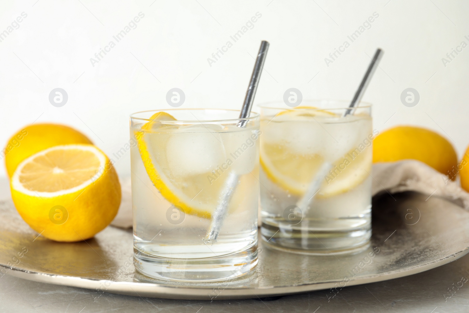 Soda water with lemon slices and ice cubes on silver tray Photo of Soda water with lemon slices and ice cubes on silver tray