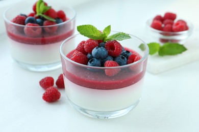 Delicious panna cotta with berries on white table Photo of Delicious panna cotta with berries on white table