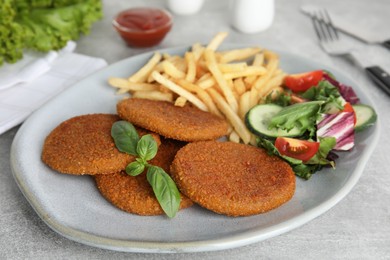 Delicious fried breaded cutlets with garnish on grey table Photo of Delicious fried breaded cutlets with garnish on grey table